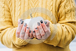 Female hands holding autumn pumpkins. Nail art concept. Holiday and party celebration. Autumn and harvest season.