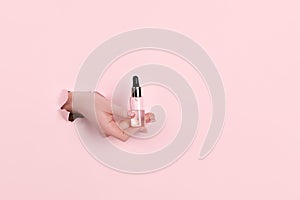Female hands holding beauty bottles on abstract pink background. Horizontal view copyspace.