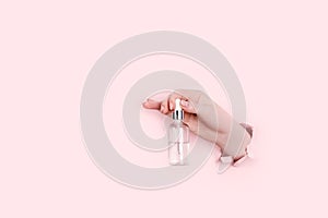 Female hands holding beauty bottles on abstract pink background. Horizontal view copyspace.