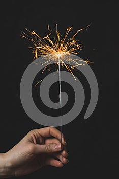 Female hands holding bengal light on black background. Christmas and newyear party sparkle