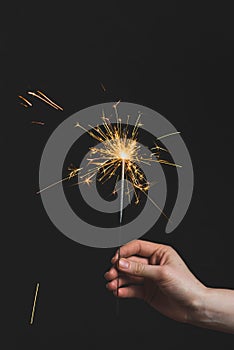 Female hands holding bengal light on black background. Christmas and newyear party sparkle