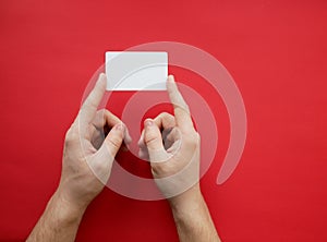 Female hands holding blank white business card on red background