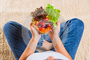 Female hands holding bowl with green lettuce salad