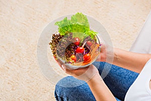 Female hands holding bowl with green lettuce salad on legs