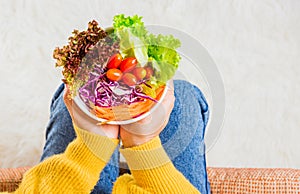 Female hands holding bowl with green lettuce salad on legs