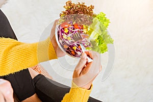 Female hands holding bowl with green lettuce salad on legs