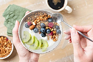 Female hands holding bowl of yogurt granola fruit bowl