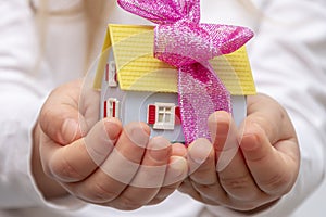 Female hands holding a bunch of keys and a toy house, light background.