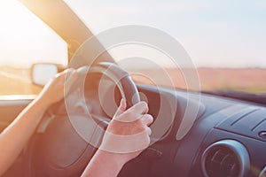 Female hands holding car steering wheel