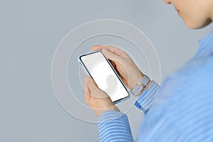 Female hands holding cell phone with mock up white mobile screen. Close up