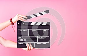 Female hands holding a clapper board isolated on pink