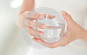 Female hands holding a clear glass of water.A glass of clean mineral water in hands, healthy drink.