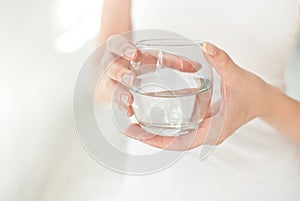 Female hands holding a clear glass of water.A glass of clean mineral water in hands, healthy drink.