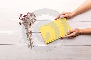 Female hands holding a closed yellow book. Opened book with white pages. Empty space for text and logo. Eco-friendly  simple style