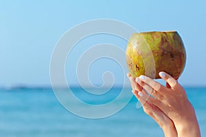 Female hands holding coconut on sea background