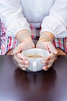 Female hands holding coffee cup on wooden table