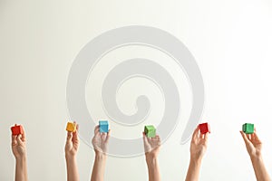 Female hands holding color cubes on light background