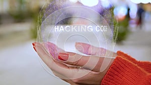 Female hands holding a conceptual hologram with text Hacking code