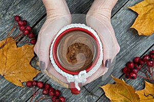 Female hands holding cup of autumn coffee.