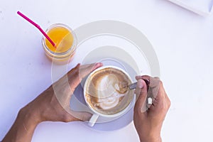 Female hands holding a cup of coffee, oranges juice besides. Healthy breakfast. top view