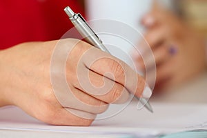 Female hands holding cup of coffee or tea and silver pen closeup