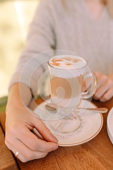 Female hands holding cup of hot latte coffee cappuccino