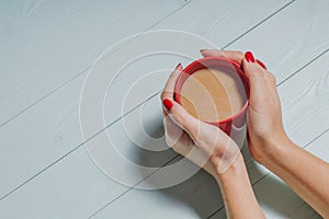 Female hands holding cups of coffee over wooden background,