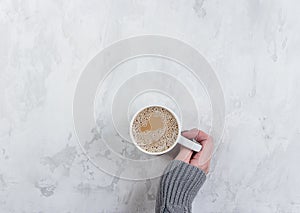 Female hands holding cups of coffee on white marble table background. Copy space, topview, flat lay