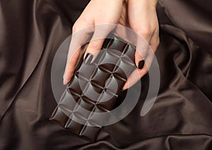 Female hands holding the dark chocolate bar