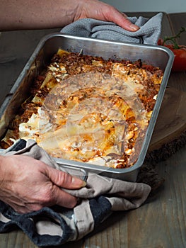 Female hands holding a delicious lasagne in a casserole