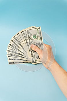 Female hands holding 100 dollar bills isolated on blue background.