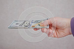 Female hands holding dollars banknotes on a grey background.