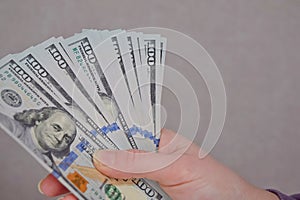 Female hands holding dollars banknotes on a grey background.