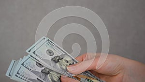 Female hands holding dollars banknotes on a grey background.