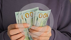 Female hands holding dollars banknotes on a grey background.