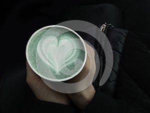 Female hands holding eco friendly cup of green matcha, Classic latte art. Empty place for text, copy space. Coffee addiction. Top
