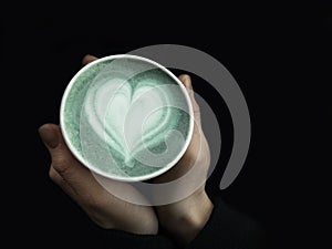Female hands holding eco friendly cup of green matcha, Classic latte art. Empty place for text, copy space. Coffee addiction. Top