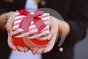 Female hands holding a gift box, present.