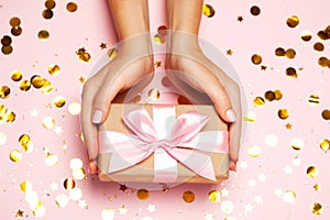 Female hands holding gift present box on festive confetti background