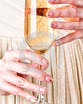 Female hands holding glass of champagne. Perfect manicure