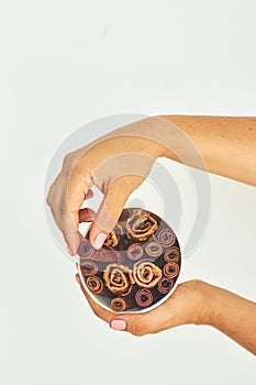 Female hands holding a glass of pastilles on a white background