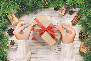 Female hands holding handmade present box in recycled paper on white wooden table background. christmas preparation concept, Gift