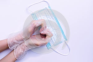 Female hands holding a heart shape over a medical mask. White background.