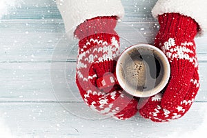 Female hands holding hot coffee above wooden table