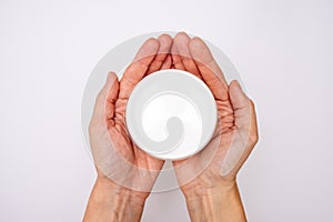 Female hands holding a jar of body skin moisturising cream, lotion on white background