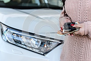 Female hands holding keys and New car in showroom