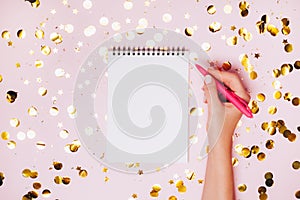 Female hands holding notebook with empt copy space on festive confetti background.