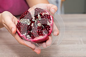 Female Hands Holding Open Pomegranate. Cradling a freshly opened pomegranate revealing juicy seeds