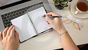 Female hands holding pen and writing on empty notebook pages