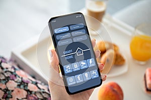 Female hands holding phone with app smart home on screen